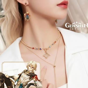 Op de afbeelding: Goudkleurige ketting- en oorbellenset. De ketting heeft een gelaagd ontwerp met kleurrijke edelsteenaccenten en een hanger. De oorbellen hebben een decoratief ontwerp met rode en blauwe accenten. De afbeelding bevat ook het logo "Genshin Impact".