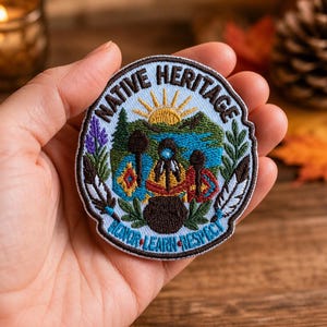 May include: A circular embroidered patch featuring a light blue background with the text NATIVE HERITAGE at the top and HONOR LEARN RESPECT at the bottom. The design includes a yellow sun, green trees, a blue river, and three figures.