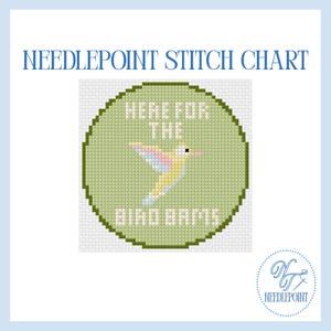 May include: Needlepoint stitch chart with a green circle featuring a hummingbird design in yellow, pink, and blue, with the text "HERE FOR THE BIRD BATHS". The chart is surrounded by a light blue border and includes the Needlepoint logo.