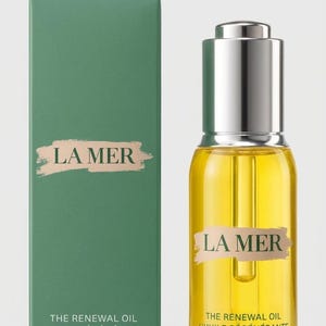May include: A rectangular green box and a clear glass bottle of La Mer The Renewal Oil. The box features the text LA MER, THE RENEWAL OIL, L'HUILE R&Eacute;G&Eacute;N&Eacute;RANTE, and 1 fl. oz. liq./30 ml. The bottle has a silver dropper cap and yellow liquid.