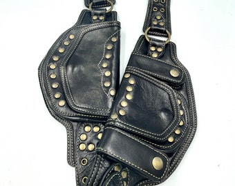 May include: Black leather belt with multiple pockets and gold-toned studs. The belt has a buckle and is decorated with stitching.
