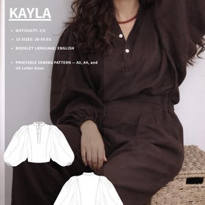 May include: A woman in a brown blouse and trousers. The image features a line drawing of the blouse design, labelled "KAYLA". Text on the image indicates the pattern difficulty, sizes, booklet language, and printable sewing pattern sizes.