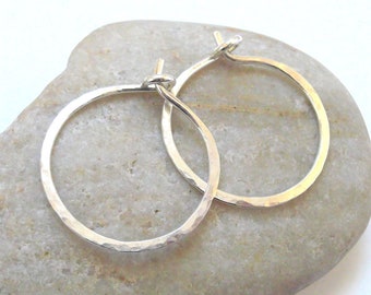 May include: A pair of silver hoop earrings with a hammered finish. The earrings are simple and elegant, and they would make a great gift for any occasion.