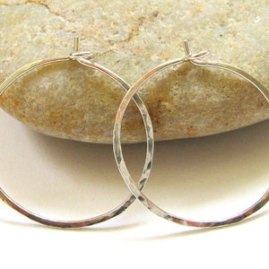 May include: A pair of silver hammered hoop earrings. The earrings are simple and elegant, and they would make a great gift for any occasion.
