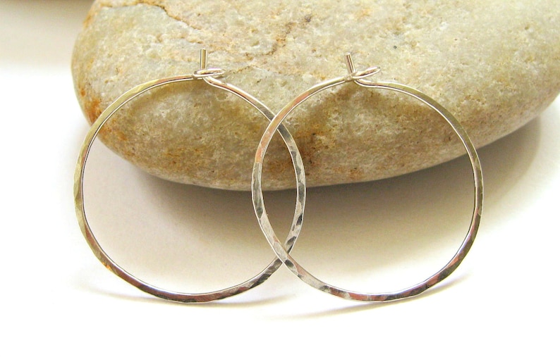 May include: A pair of silver hammered hoop earrings. The earrings are simple and elegant, and they would make a great gift for any occasion.