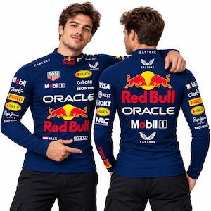Puede incluir: Una camiseta de manga larga azul oscuro con cuello alto, con logotipos de Red Bull, Oracle, Mobil 1 y varios patrocinadores. El frente muestra el logo de Red Bull, el texto Oracle y una pequeña bandera holandesa con el nombre Max. La espalda presenta la marca Red Bull.
