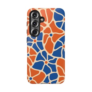 May include: A rectangular smartphone case featuring a repeating pattern of interconnected orange and blue flower-like shapes separated by thin cream-colored lines. The case has a triple-lens camera cutout on the upper left side with black rims.