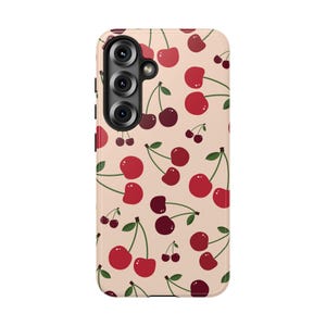 May include: A light beige smartphone case featuring a repeating pattern of cherries in various shades of red and dark maroon. Each cherry pair includes small green stems and leaves, distributed across the surface of the protective cover.
