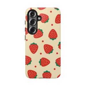 May include: A mobile phone case with a cream-colored background featuring a repeating pattern of red strawberries with green leaves and small white seeds, interspersed with tiny red dots, and a black camera lens cutout on the upper left side.
