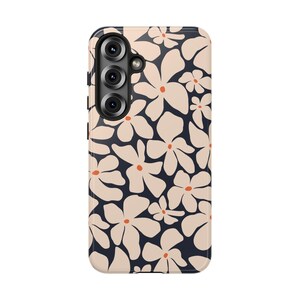 May include: A phone case featuring a floral pattern. The case has a dark navy blue background with a repeating pattern of cream-colored flowers with orange centers. The phone case has a camera module with three lenses.