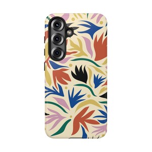 May include: A rectangular smartphone case with a cream-colored background featuring a repeating pattern of abstract organic shapes in shades of blue, red, yellow, green, black, and light pink, with a triple-lens camera cutout in the upper left.