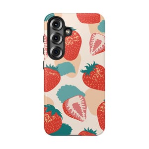 May include: A mobile phone case featuring a repeating pattern of whole and sliced red strawberries with green leaves on a light cream background. The case has a black camera module cutout on the upper left side with three circular lens openings.