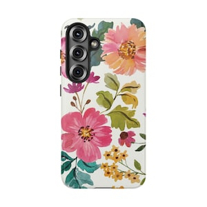 May include: A white phone case featuring a watercolor floral design. The case is adorned with pink, orange, and yellow flowers, along with green leaves. The phone case has a camera module with three lenses.