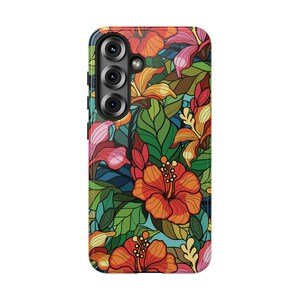 May include: A phone case featuring a vibrant floral design. The case showcases a colorful pattern of orange, red, and pink hibiscus flowers, green leaves, and blue accents. The phone's camera lenses are visible on the upper left.