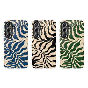 May include: Three phone cases with a leaf pattern. The cases have a black camera array. The first case is navy blue and cream, the second is black and cream, and the third is green and cream.