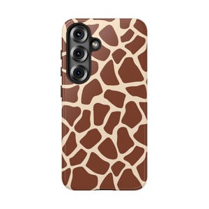 May include: A phone case featuring a giraffe print design. The case has a brown and tan pattern, with a camera module on the upper left. The case is designed to protect the phone from scratches and damage.