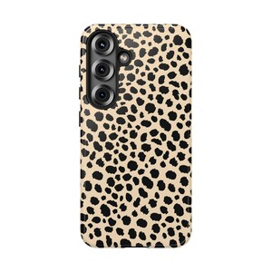 May include: A phone case with a beige background and a black animal print pattern. The case has a camera module with three lenses and a flash. The case is designed to protect the phone from scratches and damage.
