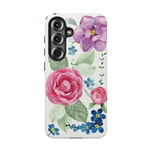 May include: A floral phone case featuring a watercolor design. The case displays pink and purple flowers, green leaves, and small blue blossoms against a white background. The case has a camera module with three lenses.