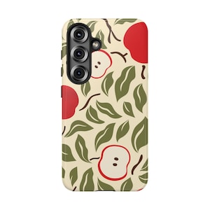 May include: A rectangular smartphone case featuring a cream-colored background with a repeating pattern of red apple halves and dark green leaves. The case includes a vertical cutout for a triple-lens camera system on the upper left side.