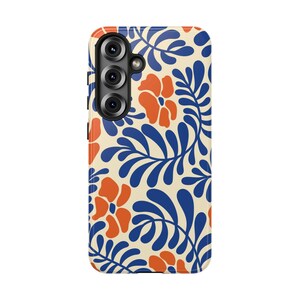 May include: A smartphone case featuring a cream-colored background with a repeating pattern of bold, dark blue fern-like leaves and vibrant orange flowers. The case has a vertical camera cutout on the upper left side with three circular lenses.