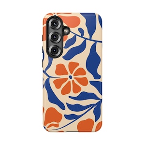 May include: A smartphone case featuring a cream-colored background with a repeating pattern of bold orange flowers and deep blue leaves. The case has a cutout for a triple-lens camera system on the upper left side and black side buttons.