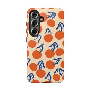 May include: A rectangular mobile phone case featuring a repeating pattern of orange circular fruit shapes with dark blue stems and leaves against a light beige background. The case includes a vertical camera cutout on the upper left side.