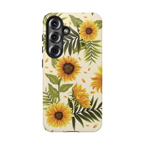 May include: A rectangular mobile phone case featuring a cream-colored background decorated with a pattern of vibrant yellow sunflowers and green palm-like leaves. The case includes a black camera cutout section on the upper left side.