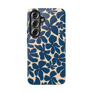 May include: A phone case featuring a floral pattern. The design includes navy blue flowers with orange centers on a cream-colored background. The case has a camera module with three lenses.