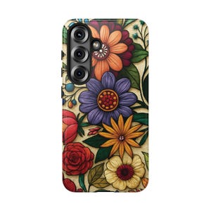 May include: A phone case featuring a vibrant floral design. The case showcases a variety of colorful flowers, including orange, purple, yellow, and red blooms, set against a beige background. The design includes green leaves and stems, creating a lively and artistic pattern.