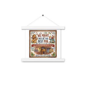 May include: A square wall hanging with a white wooden frame featuring a cartoon illustration of a lion and a person holding beer mugs. The text reads: We might not be the best pub... but we are the only one that lets you in! The design includes a pub entrance.
