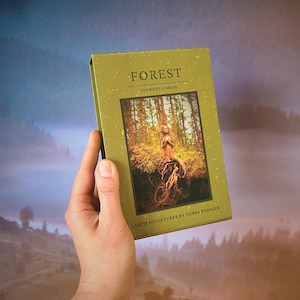 May include: A rectangular deck of Forest Journey Cards in a green box with a speckled texture. The front features the text Forest Journey Cards and Earth Sculptures by Debra Bernier, with a central image of a sculpted figure made of tree roots.