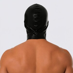 May include: A black hood made of a shiny material, covering the head and neck. The hood is smooth and form-fitting, with a seam running down the back. The image is shot from behind, showing the back of the head and shoulders.