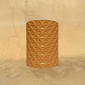 May include: A white ceramic mug with a black handle and the text "But First, Coffee" in a bold, black font. The mug is set against a blurred background, suggesting a cozy setting.