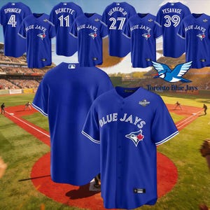 Può includere: Maglie da baseball blu reale con dettagli bianchi. Diverse maglie presentano nomi e numeri di giocatori, tra cui "SPRINGER 4", "BICHETTE 11", "GUERRERO JR 27" e "YESAVAGE 39". È visibile anche il logo "Toronto Blue Jays".