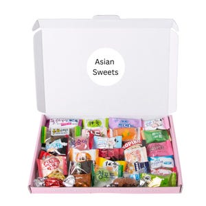 May include: A white box with a pink interior, packed with an assortment of individually wrapped Asian sweets. The box has a white circular sticker that reads "Asian Sweets". The sweets are in various colours and packaging.