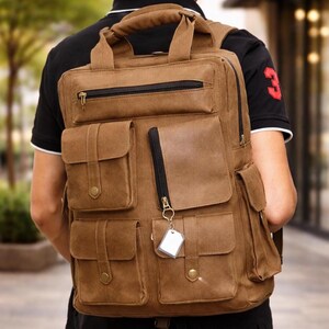 May include: A brown canvas backpack with multiple pockets and a top handle. The backpack has a rectangular shape with a zippered main compartment and several smaller pockets on the front. A small tag hangs from a zipper.
