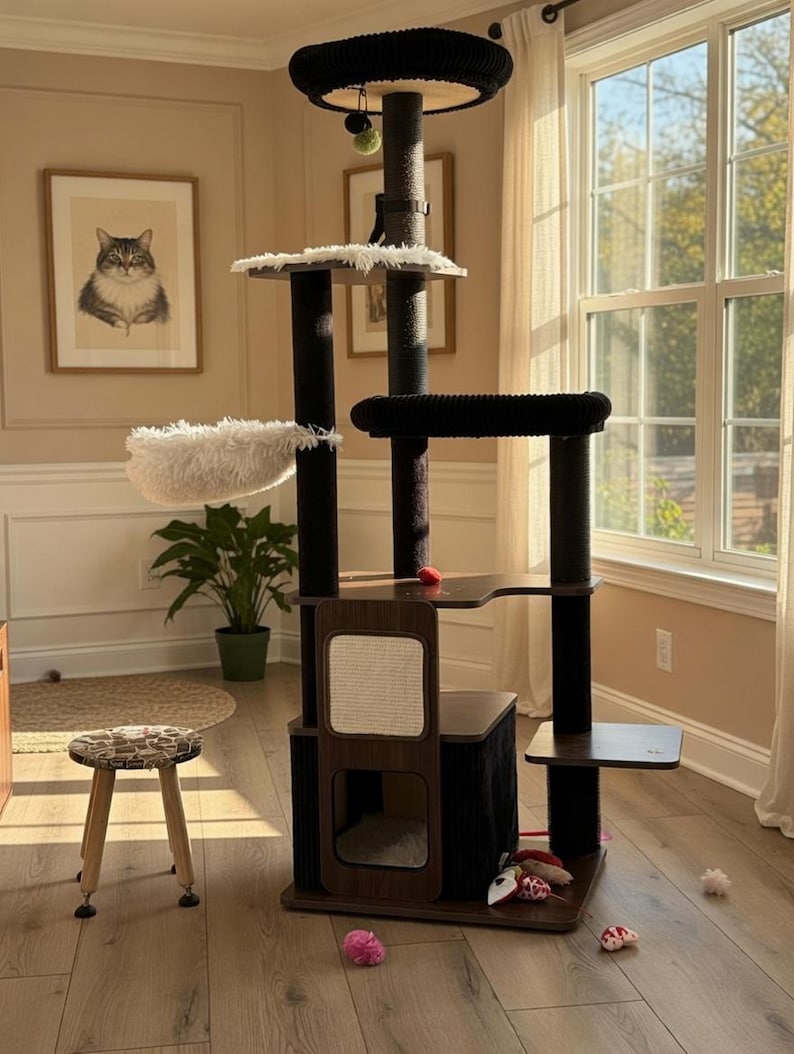 May include: A multi-level cat tree with a dark brown and black color scheme. It features multiple platforms, a plush bed, scratching posts, and a hanging toy. The cat tree is placed in a room with a framed cat portrait and a small stool.