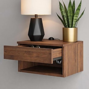 May include: A floating wooden nightstand with an open drawer, a black lamp with a white lampshade, and a potted snake plant. The nightstand is made of dark wood and has a lower shelf. The lamp has a geometric base.