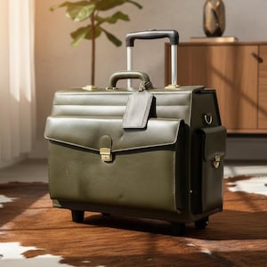 Puede incluir: Maletín rodante verde oliva con asa telescópica y múltiples compartimentos. El maletín tiene una textura similar al cuero, herrajes dorados y una etiqueta de equipaje. Diseñado para viajes de negocios.