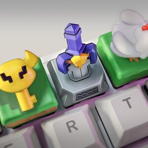 May include: A close-up of a mechanical keyboard with custom keycaps. The keycaps feature a yellow key, a purple sword, and a white chicken. The keycaps are on a white keyboard with black keys.