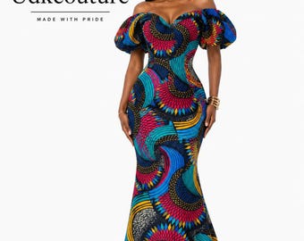 May include: A floor-length off-the-shoulder dress featuring a vibrant multicoloured geometric pattern in shades of blue, pink, yellow, and black. The garment has puffed short sleeves, a sweetheart neckline, and a fitted bodice that flares at the hem.