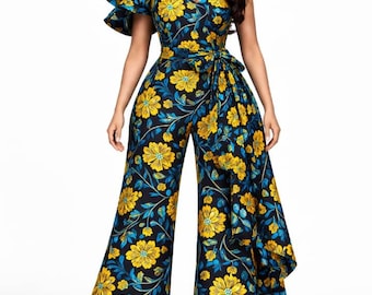 May include: A one-shoulder jumpsuit with a floral pattern in yellow and blue on a black background. The jumpsuit features a ruffled sleeve, a tie-waist, and wide-leg pants. The brand name "Udkcouture" is visible at the bottom.