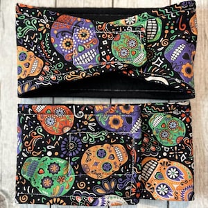 Puede incluir: Dos diademas de tela negra con un estampado colorido de calaveras de azúcar del Día de Muertos. Las diademas están hechas de una tela suave y elástica y son perfectas para añadir un toque de diversión espeluznante a cualquier atuendo.