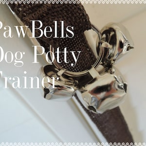 May include: A brown dog potty training bell with the text "Paw Bells Dog Potty Trainer" on it.