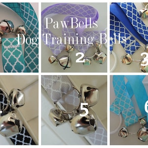May include: Six different dog training bells with various colored ribbons. The bells are silver and attached to a ring. The ribbons are patterned with a geometric design. The text "Paw Bells Dog Training Bells" is visible in the image.