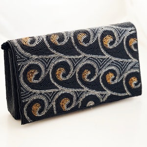 May include: A black beaded clutch with a swirling pattern of silver and gold beads.