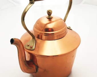 May include: A copper kettle with a wooden handle and brass accents. The kettle has a shiny, polished finish.