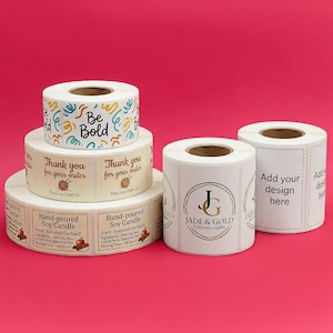 May include: Several rolls of white labels with various designs and text. One roll says "Be Bold" with colorful swirls. Other labels say "Thank you for your order" and "Hand-poured Soy Candle". There are also labels for "Jade & Gold" and "Add your design here".
