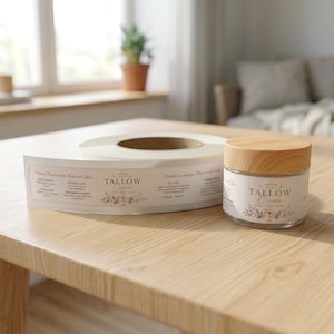 May include: A clear glass jar of Tallow Cream with a light wood grain lid, accompanied by a roll of matching adhesive labels. The labels feature floral illustrations and text including Tallow Cream, Natural Glow, and Rooted in nature.