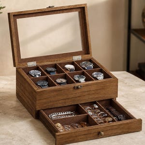 May include: A dark brown wooden watch box with a glass lid, featuring eight individual compartments for watches in the top section and a pull-out drawer below with multiple dividers for storing jewellery, chains, and additional watch accessories.
